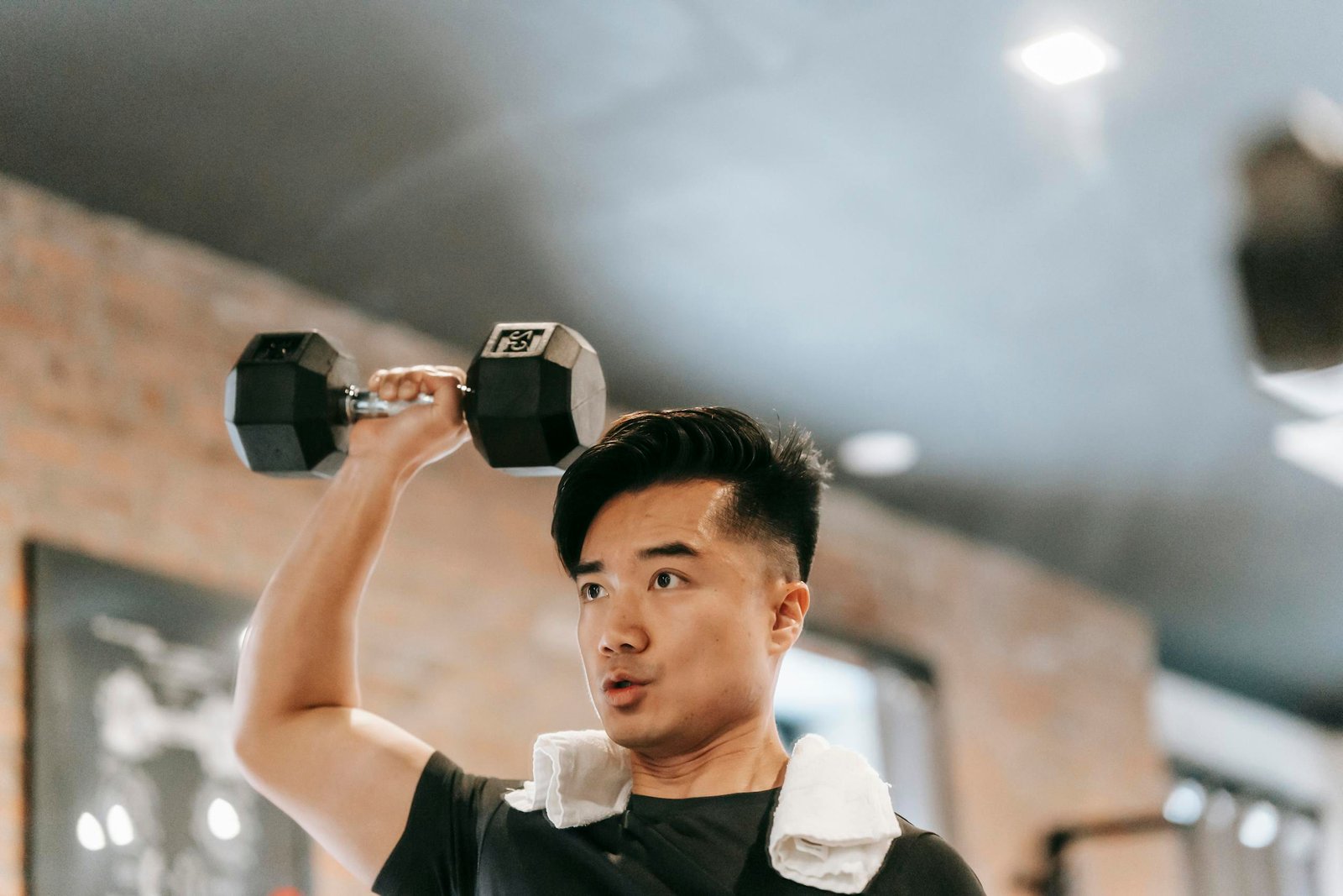 Muscular Asian man lifting dumbbell in gym