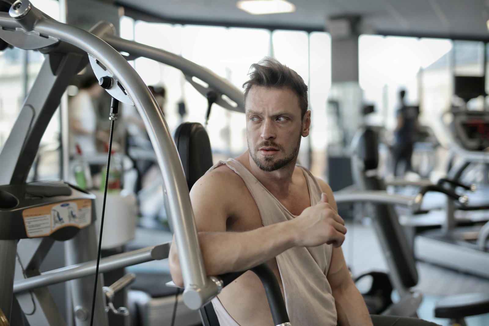 Brutal sportsman resting on exercise machine in gym