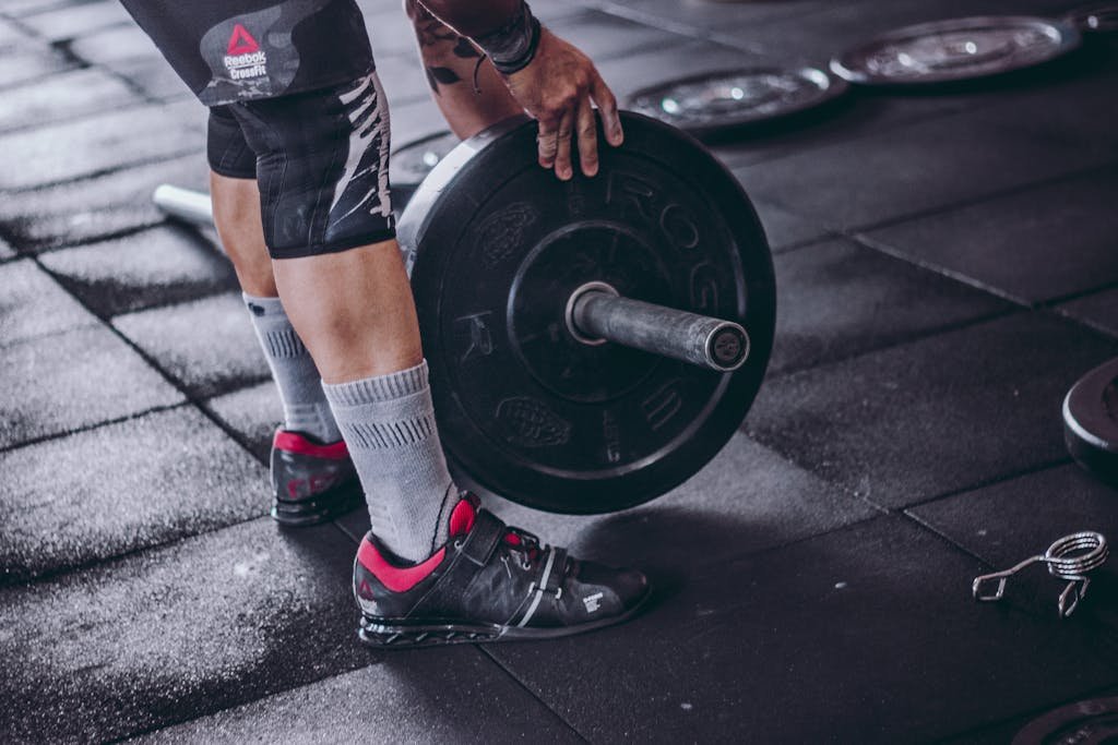 Man Picks Up Black and Grey Barbell