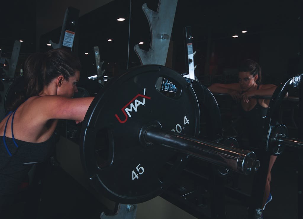 Woman Leaning on Black Barbell in Front Mirror