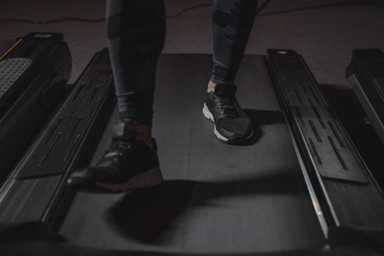 Feet running on treadmill in gym. Focus on black sneakers. Fitness and cardio exercise concept.