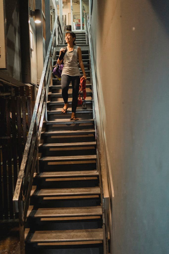 Smiling woman walking downstairs with belay and backpack